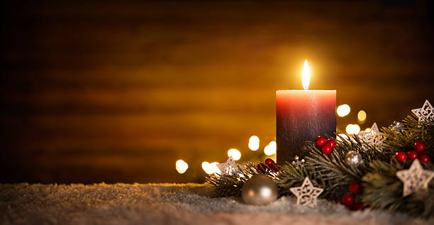 Candle and Christmas decoration with wooden background Burning candle and Christmas decoration over snow and wooden background, elegant low-key shot with festive mood christmas decore candle stock pictures, royalty-free photos & images