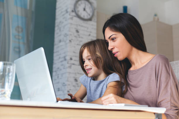 istock Cute girl and mother using laptop at home 621828552