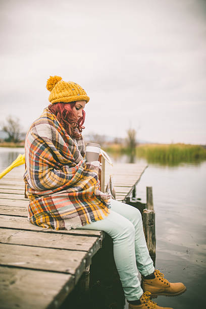 istock Lonely woman sitting on the dock on cold winter day. 621829178