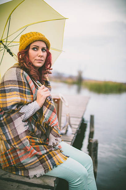istock Women waiting on the river dock with umbrella 621830356
