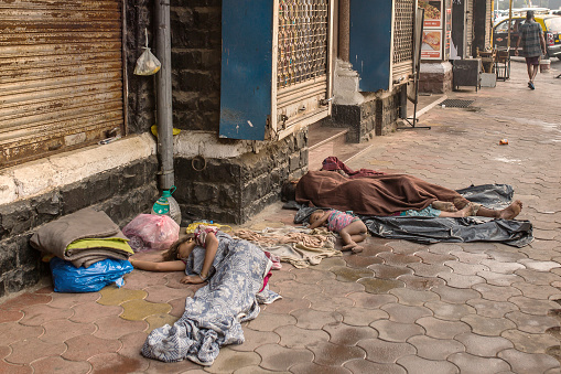Mumbai, India - February 28, 2016: Unidentified  poor people sleep at the street in Mumbai, India. Over 90 million people in India make less than 1 USD per day, setting them below global poverty threshold.