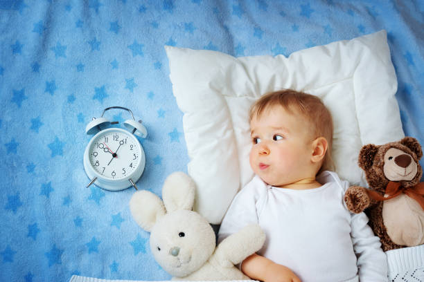 istock One year old baby with alarm clock 621833784