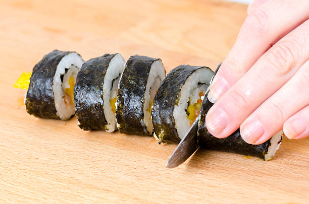 istock knife in hand cuts the roll closeup. 621834332