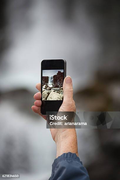 Female Senior Traveler Photographing With Smartphone The Waterfa Stock Photo - Download Image Now