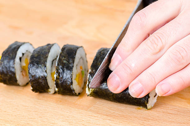 istock knife in hand cuts the roll closeup. 621834726