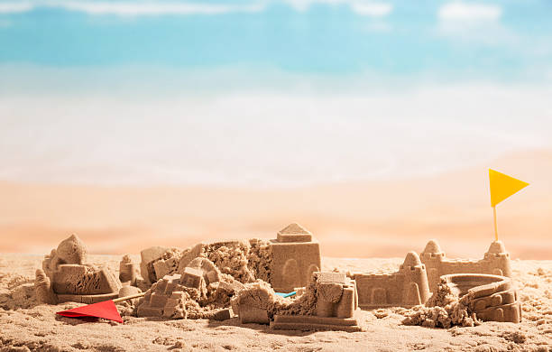 istock Shattered sand castles, towers and flags Coliseum on background sea. 621837248
