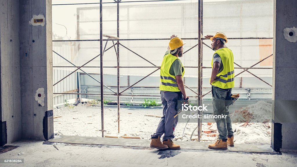 Construction workers discussing Construction workers wearing reflective clothing discussing at construction site. Construction Worker Stock Photo