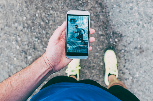 Point of view of runner outside looking at a mobile phone with a running or fitness app. There are also some numbers on the screen to show the progress of sports training. 