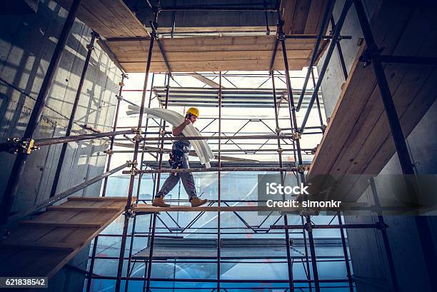 Worker Carrying Pipes Stock Photo - Download Image Now - Scaffolding, Construction Industry, Construction Site