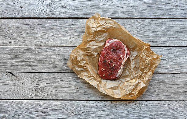 istock Raw beef steak on dark wooden table background, top view 621839024