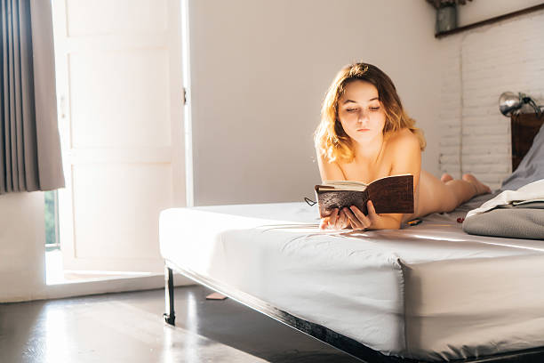 Mental health care, positive thinking and wellness concept. Attractive woman lying in bed, practicing stress relief challenge with journal about feeling, glass of water and gratitude list