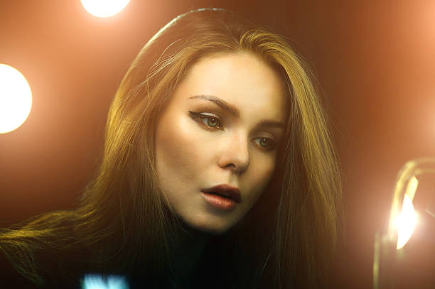 istock Young caucasian woman looking into makeup mirror. Golden light rays. 621841066
