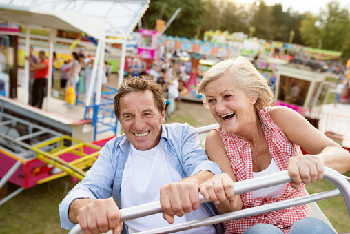 Senior couple having fun on a ride in amusement park. Summer vacation.
