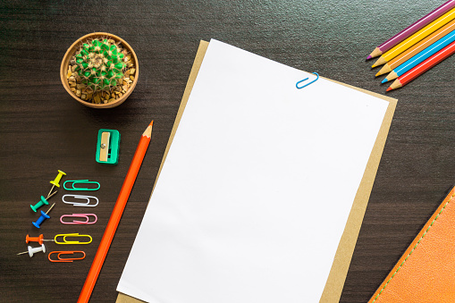 Blank white paper and colored pencil on the desk.