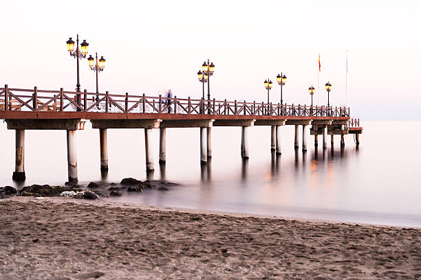 Illuminated wooden jetty on a beach in Marbella during sunset. Long exposure.