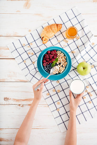 istock Hand holding spoon with cereal breakfast and cup of milk 621847964