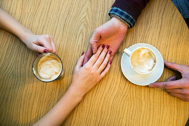istock Man holds woman's hand with cup of coffee 621848132