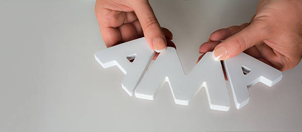 woman holding  the acronym AMA Ask me Anything in white wooden letters