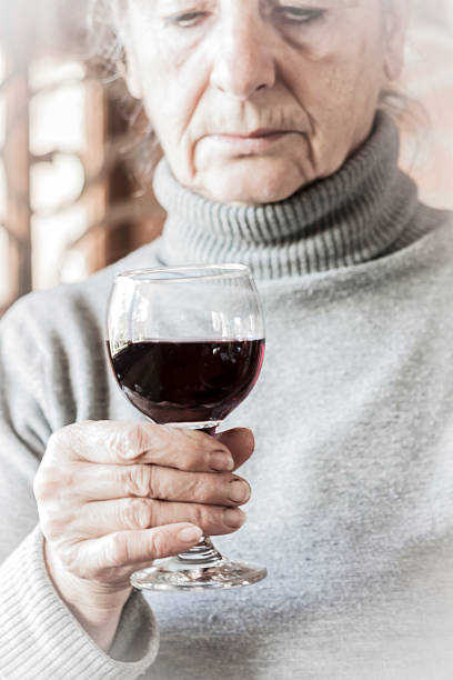 Sad woman holding a glass of red wine stock photo