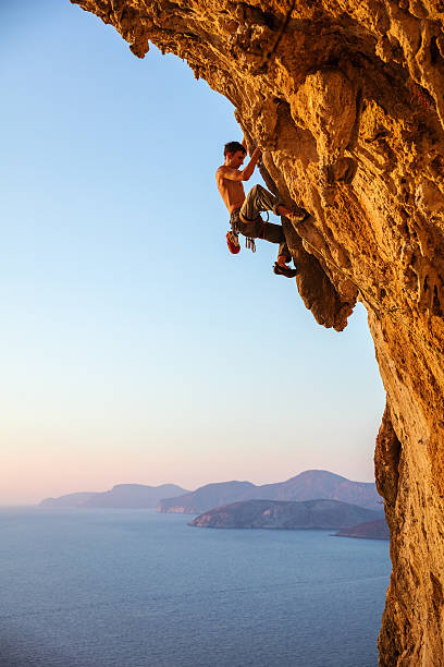 rock alpinista no saliente cliff - climbing men sea cliff imagens e fotografias de stock