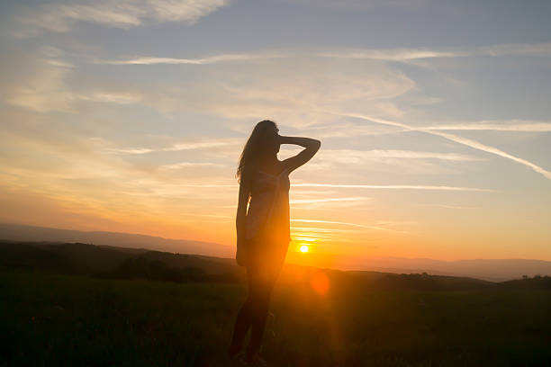 Silhouette of young woman looking to a sunset.