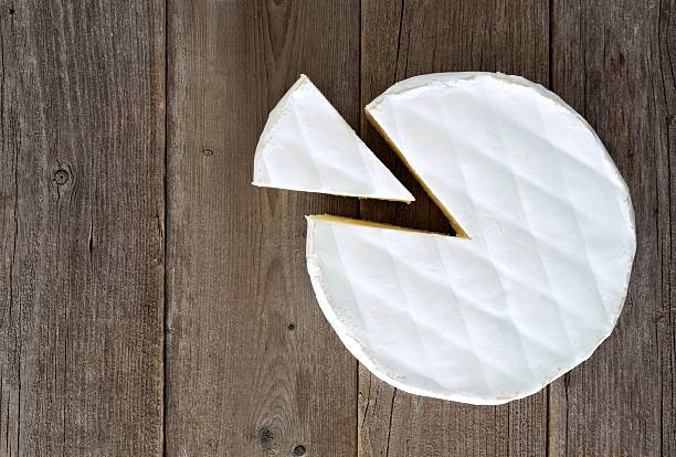 istock Brie cheese with cut slice, above view on rustic wood 621853384