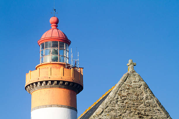 istock tip of a a lighthouse and a chapel 621853404