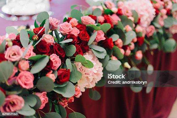 Festón De Flores Con Rosas Maravillosas Se Encuentra En La Mesa Roja De La Cena Foto de stock y más banco de imágenes de Accesorio personal - iStock Festón De Flores Con Rosas Maravillosas Se Encuentra En La Mesa Roja De La Cena Foto de stock y más banco de imágenes de Accesorio personal - iStock