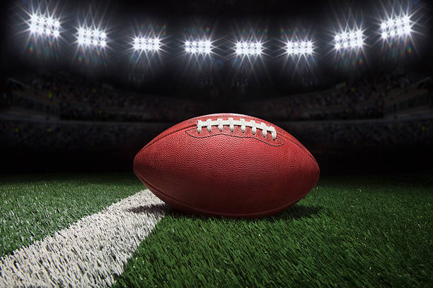 istock Professional style football on field with stripe under stadium lights 621894138