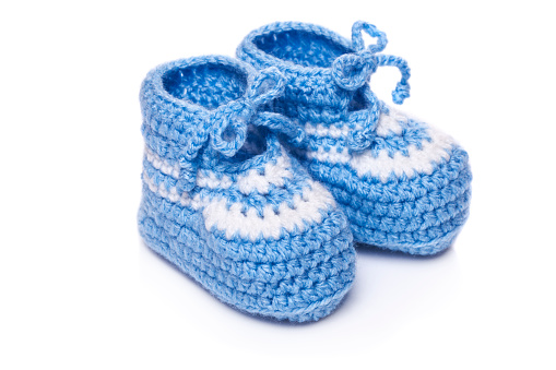 Homemade knitted baby blue booties isolated on white background