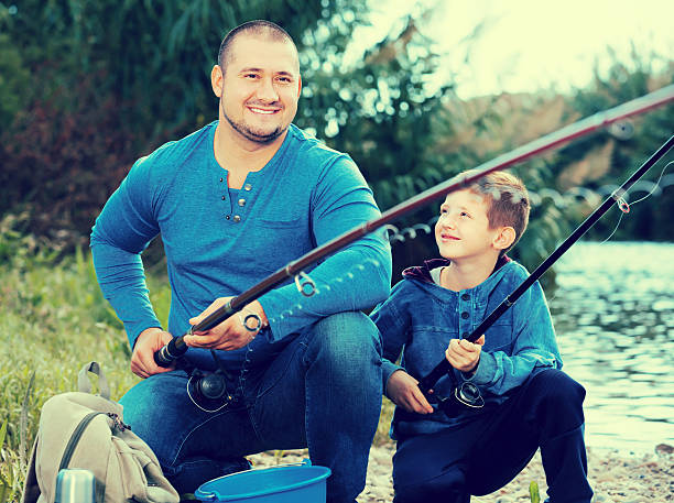 istock Glad father and boy fishing with rods 621894844