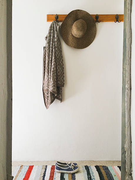 Walk in a Park A coat and a hay cap hanging on the wall. Espadrilles underneath. Colorful rug. coat hook photos stock pictures, royalty-free photos & images