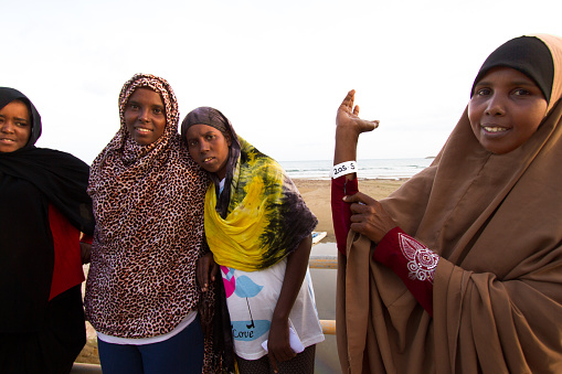 Pozzallo, Sicily, Italy - November 5, 2016: Just-arrived Somali (female) migrants to Sicily's shores; one is showing her ID wristband. The beach and Mediterranean Sea are in the background. Pozzallo is in Ragusa Province.