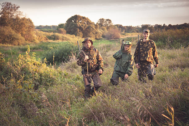 istock Hunters going through tall garass in rural field at dawn 621900378