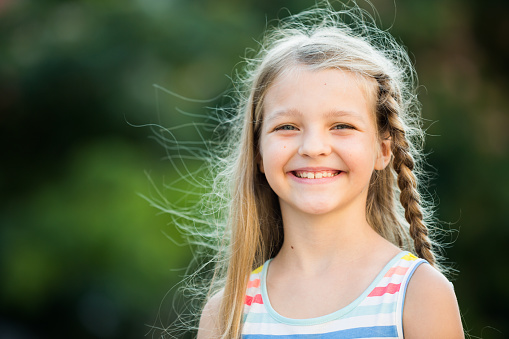 closeup portrait of happy girl in elementary school age outdoors