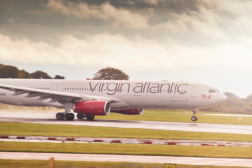 Manchester, UK - October 16, 2016: Virgin Atlantic Airbus A330-300 speeds down the runway at Manchester Airport. The plane has has it's front wheel off the ground as it is in the process of taking off.