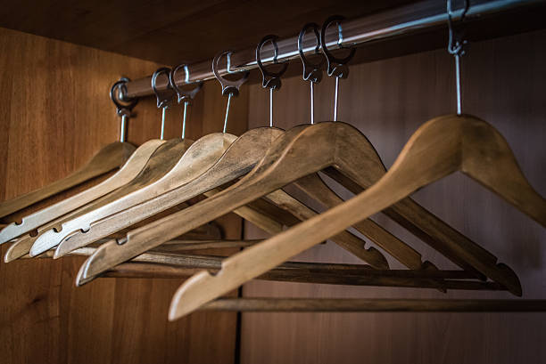 Closeup of wardrobe metal rod with empty clothes wooden hangers. Close up of a wardrobe metal rod with empty clothes wooden hangers. clothes hanger rod stock pictures, royalty-free photos & images