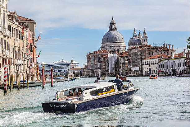 Venice, Italy - October 11, 2016: The church Basilica di Santa Maria della salute in Venice, Italy. Tourists are passing by in front on Canale Grande in water taxis and on a big cruising ship in the back. Venice is a famous italian city with lots of canals. It is situated on lots of small islands and is famous for the gondolas shipping on the water.
