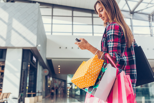Young woman with shopping bags texting on smartphone