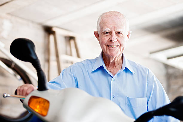 smiling 90-year-old man sits on his motor scooter - 80 year old imagens e fotografias de stock