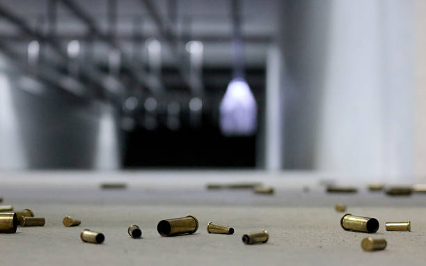 Spent Bullet Casings on the floor A variety of different shell casings spread across the floor at a shooting range with target in the background. gun control photos stock pictures, royalty-free photos & images