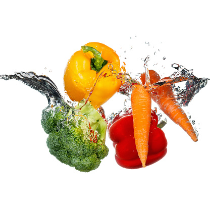 Vegetables thrown into a water. Splashes and drops