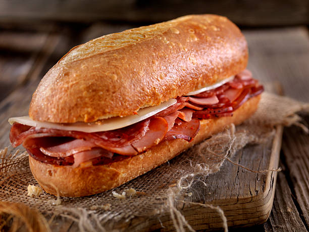 sandwich italien avec salami, gênes, prosciutto et provolone - sandwich submarine sandwich ham bun photos et images de collection