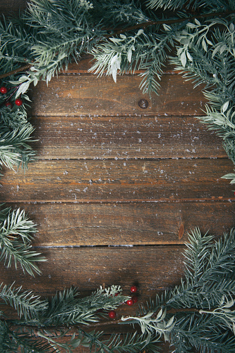 Christmas background with fir branches on wood, sprinkled with snow.