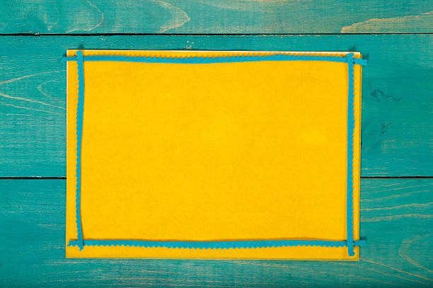 Yellow felt fabric on a cyan wooden surface. Background. Closeup