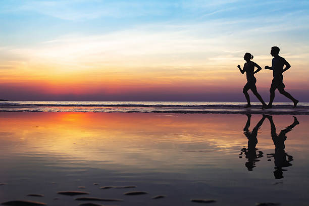 dwóch biegaczy na plaży, sylwetka - sun people jogging sunset zdjęcia i obrazy z banku zdjęć