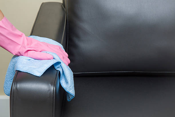 istock Hand in pink protective glove wiping leather sofa with cloth. 621933774