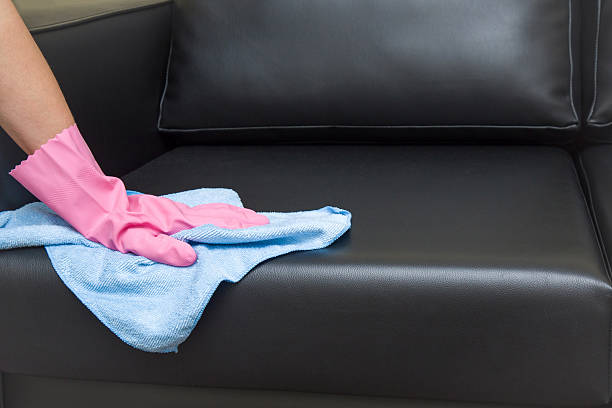 ピンクの保護手袋で布で革のソファを拭きます。 - foundation bed ストックフォトと画像