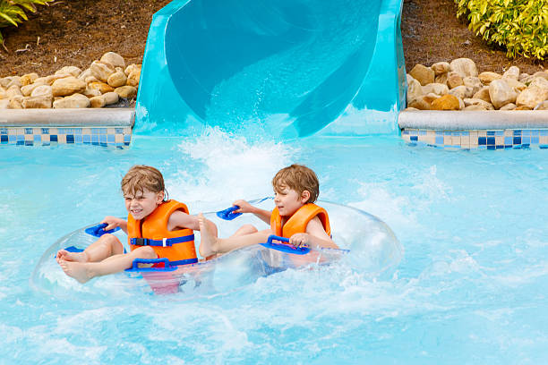 istock excited children in water park riding on slide with float 621934596