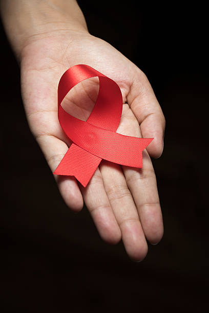 istock Red ribbon awareness on woman hand 621937142